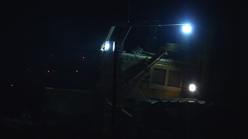 This is a shot of a firefighter's bulldozer starting up at night in a cloud of ash from the 2010 Crown Fire in Palmdale, California