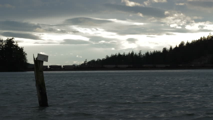 A time lapse of sparse clouds over Chuckanut Bay, with a stationary train in the background.