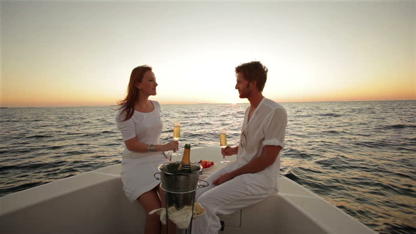 couple drinking champagne on boat at sunset 