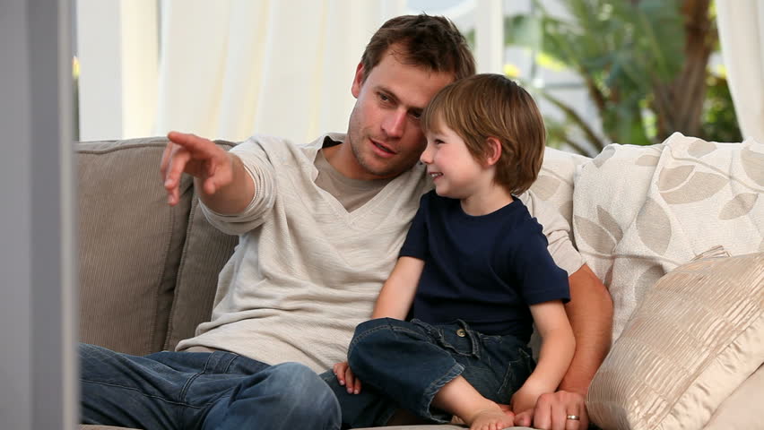 Attentive father watching tv with his son