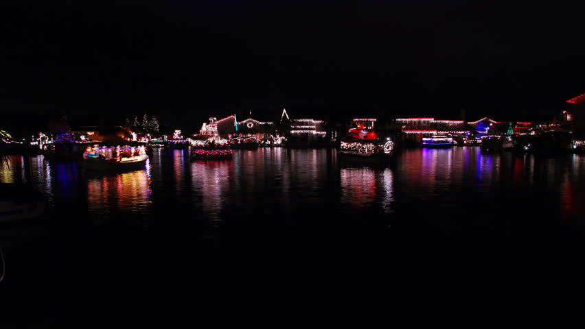 Boat parade on a lake with Christmas lights reflecting on the water - part one - HD. 