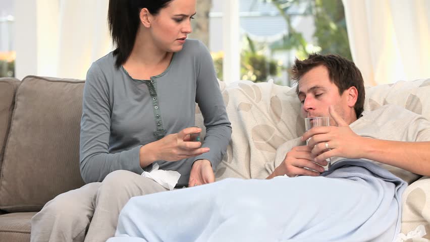 Worried woman giving pills to her sick husband
