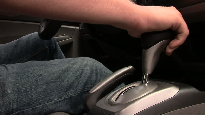 Young man putting on emergency break and taking keys out of ignition of car