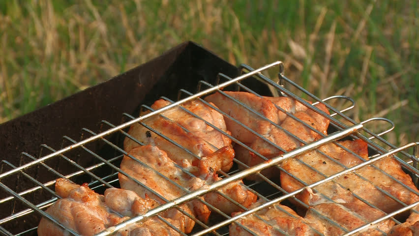 HD. large chunks of meat roasting on the fire braziers in the metal lattice