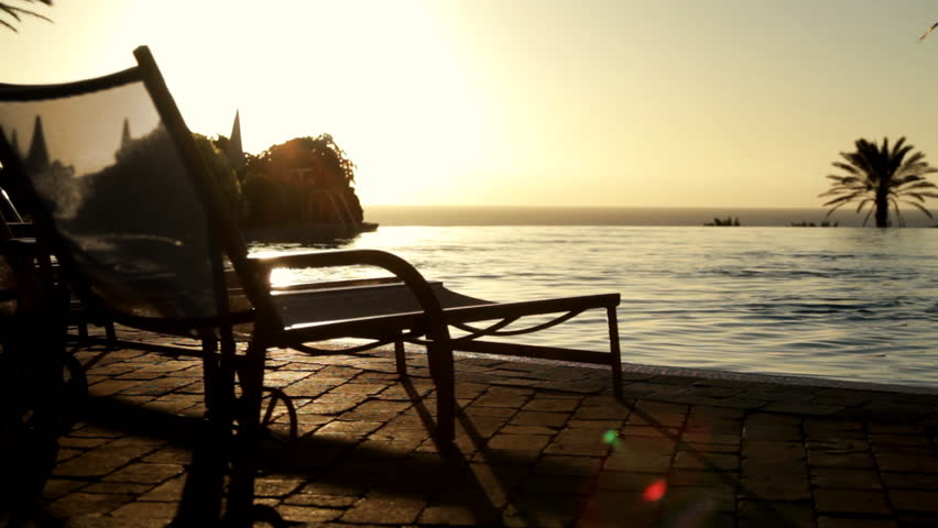 Sunbed by the infinity pool at sunrise 