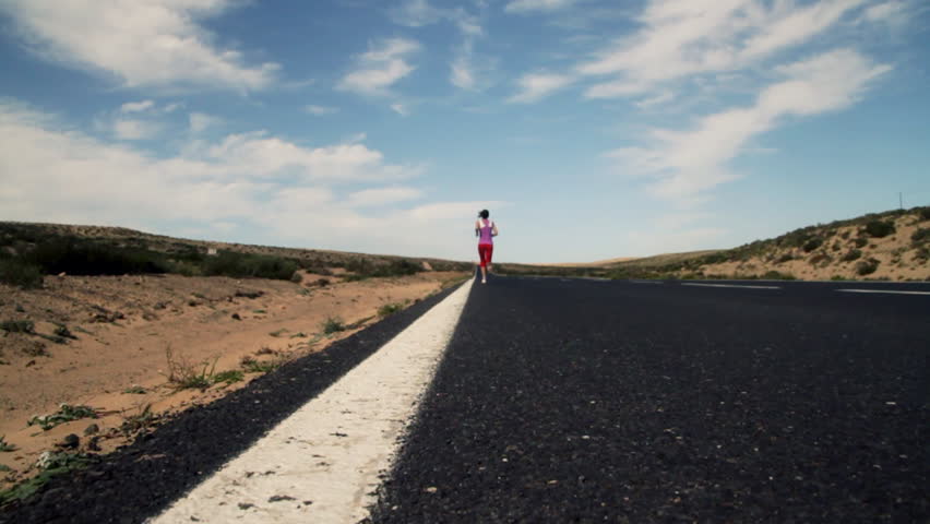 Young woman jogging on country road, dolly shot, slow motion