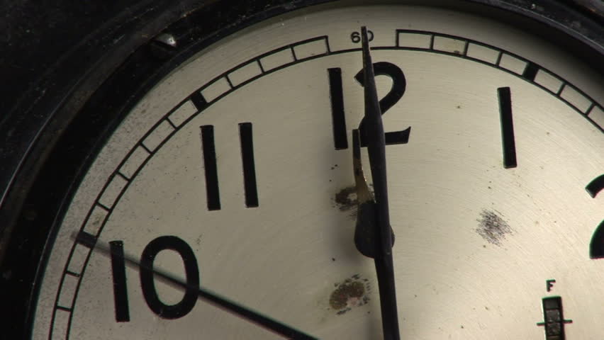 A close up of an old clock, with the hands straight up at twelve oÃ¢â¬â¢clock and the second hand moving