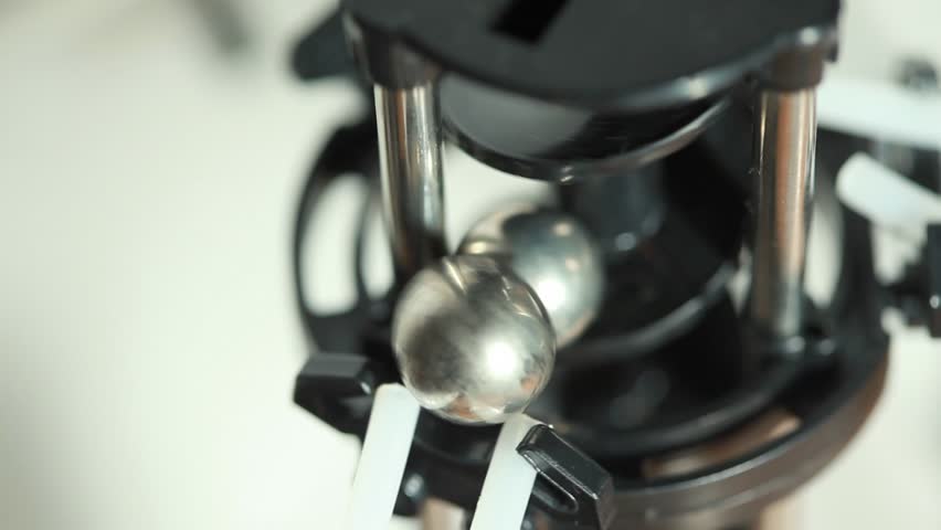 closeup of two iron balls lift and drop with mechanism