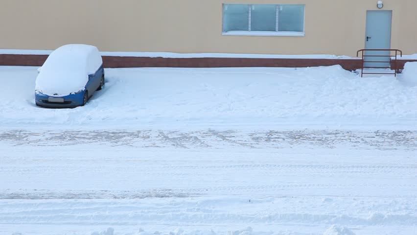 tractor cleans snow on road, moves down street in winter 