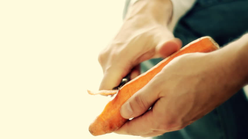 Male hands peeling carrot, close up