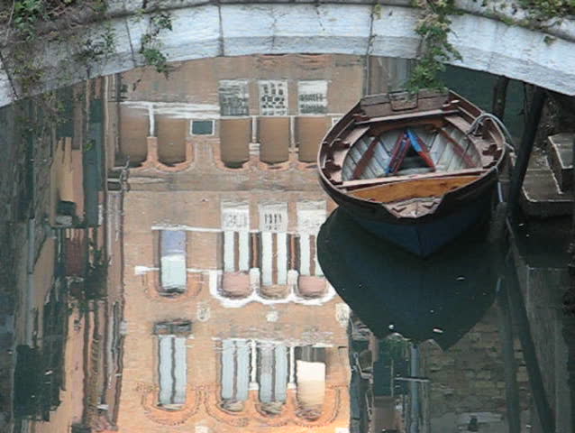 Venice: Building reflections and old wooden boat under a bridge