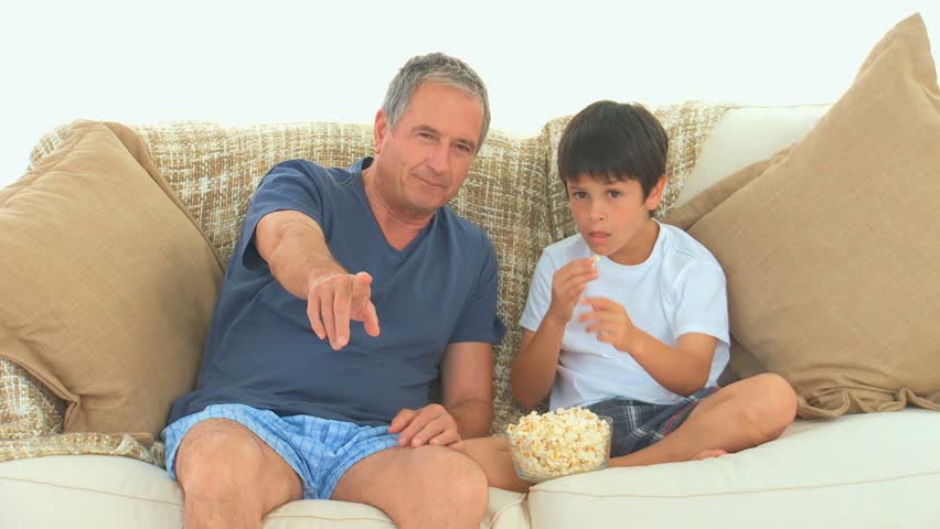 Grandfather and his grandson watching a match with popcorn