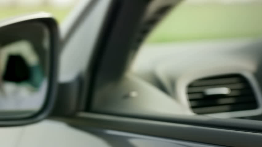 mid adult caucasian business man looking at camera through rear view mirror. Dolly shot