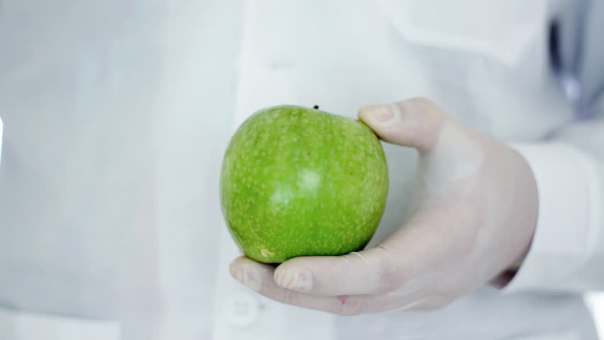 Male scientist hands with syringe injecting green apple