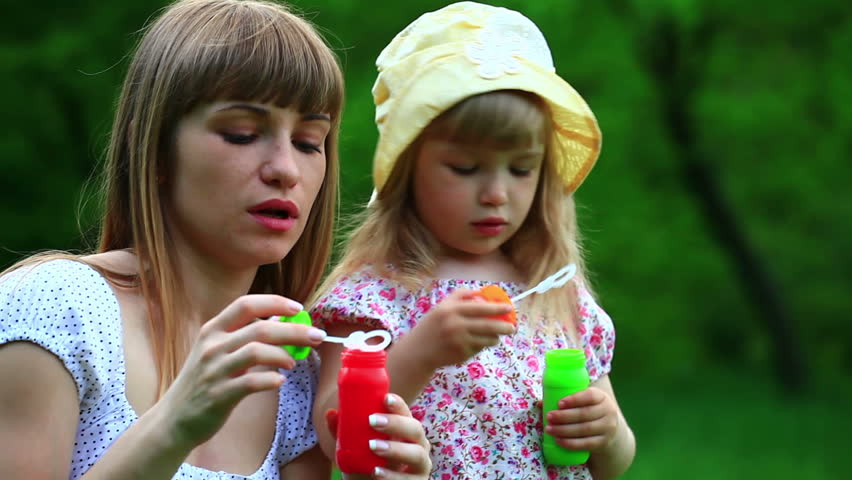 Mother and daughter with soap bubbles. Mother kissing baby 
