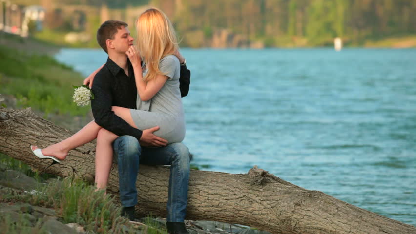 loving couple sitting on a fallen tree trunk near the shore of Lake