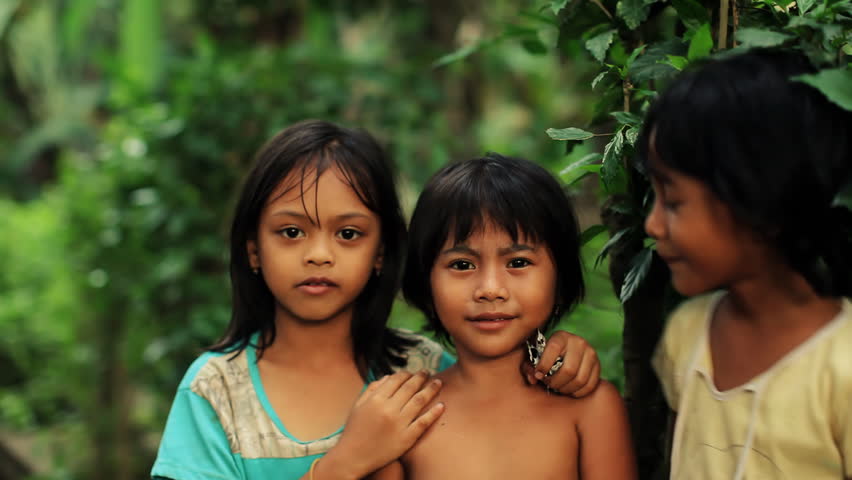 Three native Balinese girls posing playful for camera, changing places, laughing and having fun