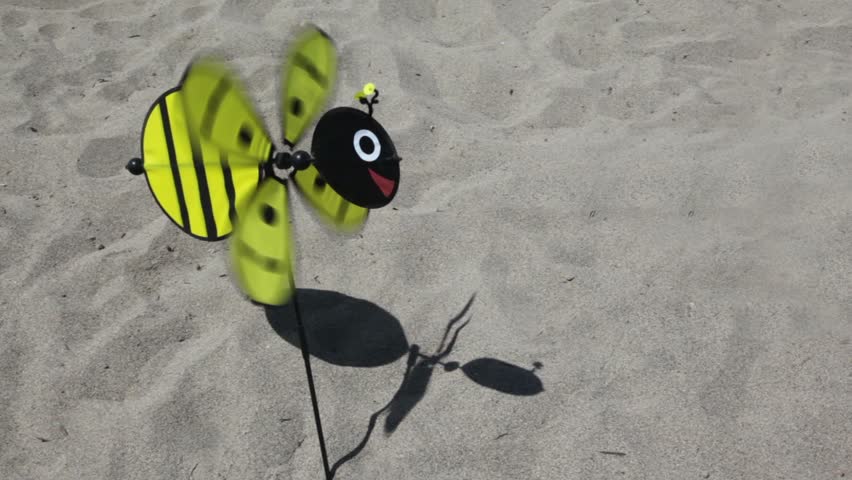 Toy in the shape of a bee with a rotating propeller stuck in the ground, the propeller rotates, a toy sways