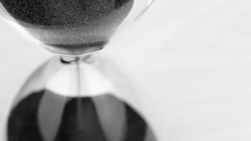 hourglass in black and white ticking time away slowly, sense of urgency