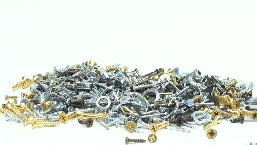 Red horseshoe magnet swings across pile of assorted nails, screws and washers, attracts a large clump, lifts it, twirls around, slowly descends, drops onto pile. 1080p