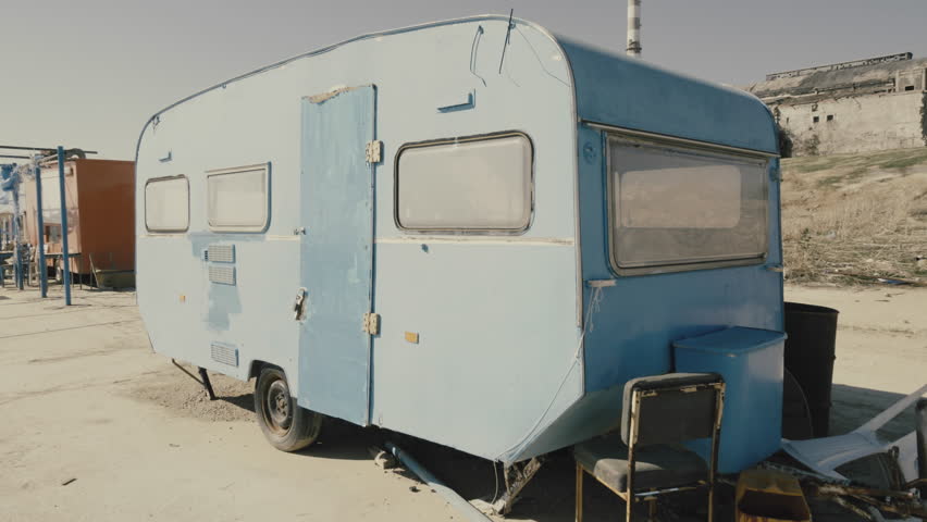 Rickety Old Vintage Abandoned Caravan Trailer In A Deserted Camp AreaAn Rusty Near Pier Close To An Industrial CampPanning Shot Rickety Old Vintage Abandoned Caravan Trailer In A Deserted Camp AreaAn Rusty Near Pier Close To An Industrial CampPanning Shot