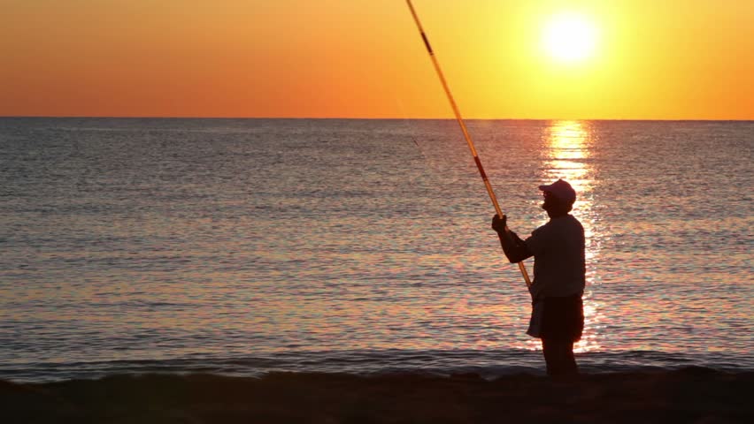 Man casts a fishing rod, and then beckoning fish, on sea at evening