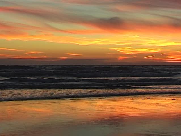 Dramatic sunset on a beach with a bird flying across the shot. With Audio.