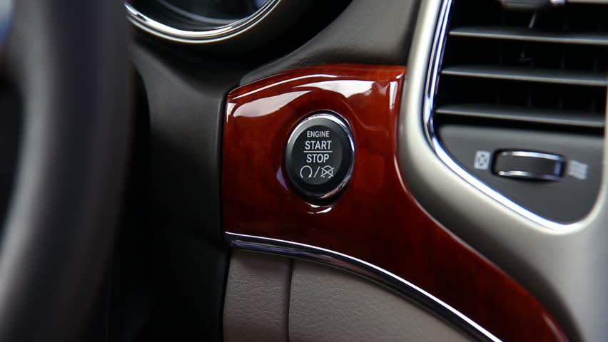 Pushing the keyless start button on a car's dashboard.