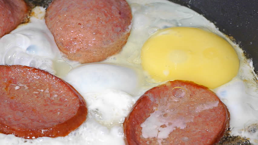 pieces of sausage and egg cook on frying pan