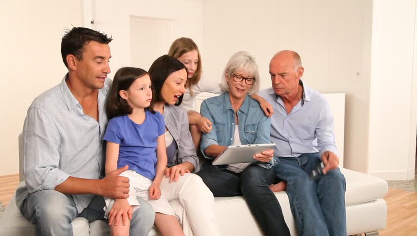 3-generation family sitting in couch with electronic tablet