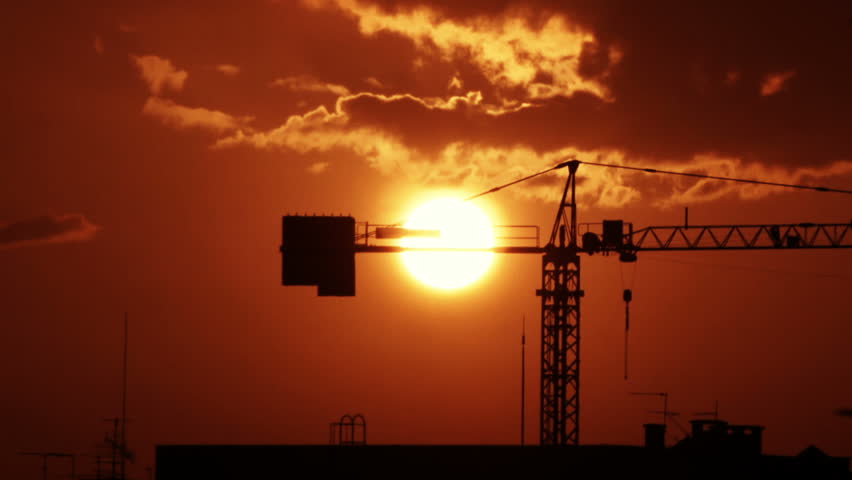 Time-lapse of a sunset behind a construction crane. 