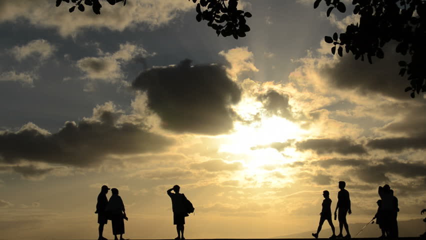 People walking, jogging, fishing at a park by the beach at sunset in Hawaii