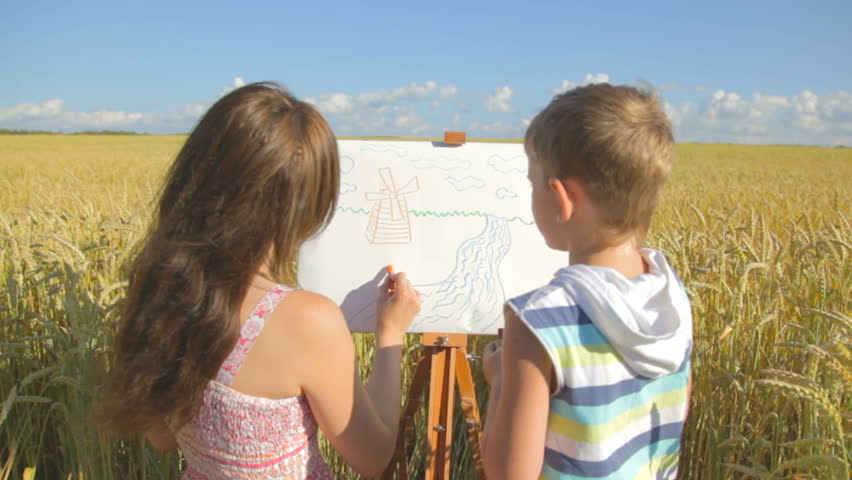Young woman with little boy drawing landscape with crayons 