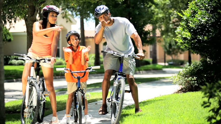 Healthy young ethnic parents keeping fit together with their son out cycling
