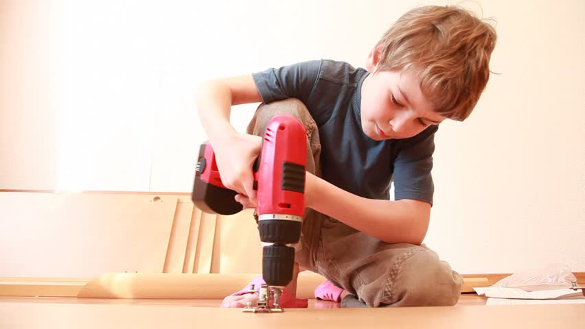 Boy use screwdriver while construct furniture element