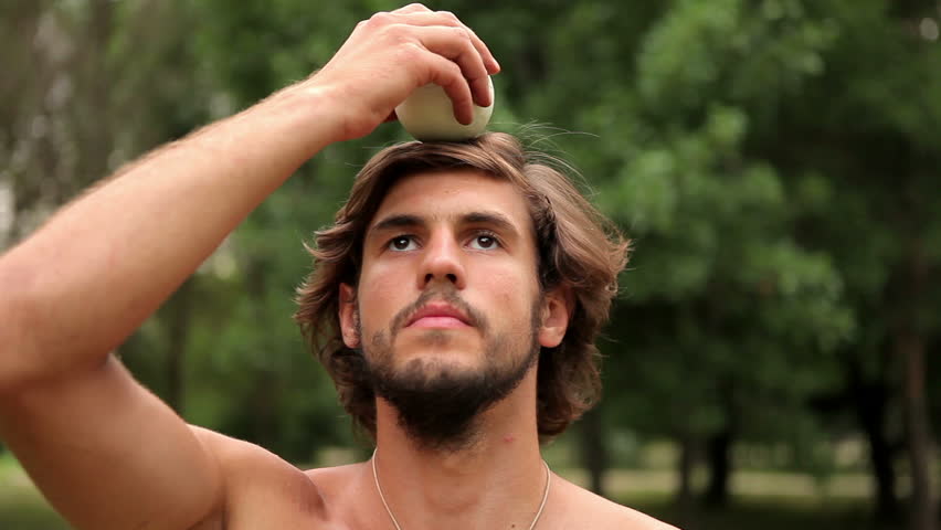Guy tries to balance the ball on his head. Close-up