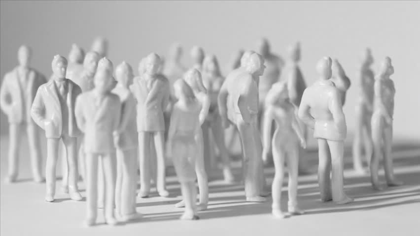 Group of little unpainted toy men and women stand and drop shadows, composition rotates, sideview