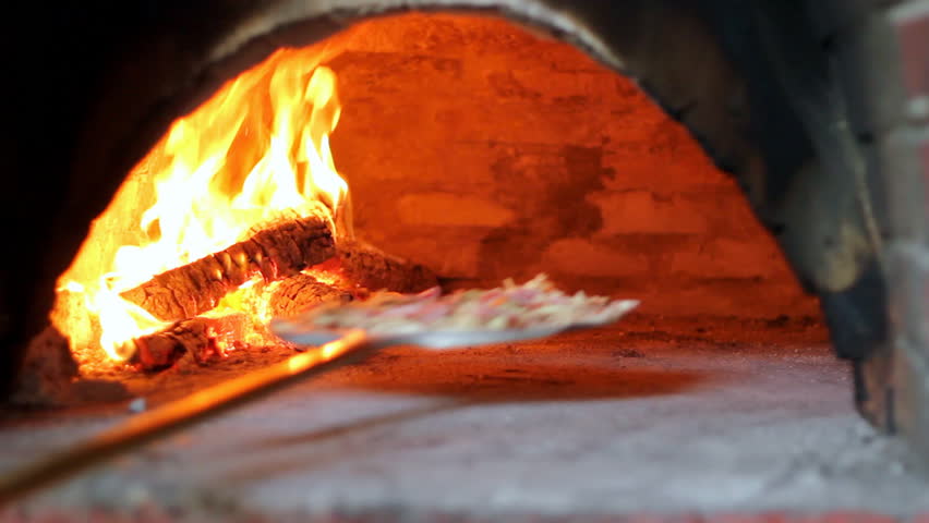 Chef loading pizza into hot oven. HD 1080i.