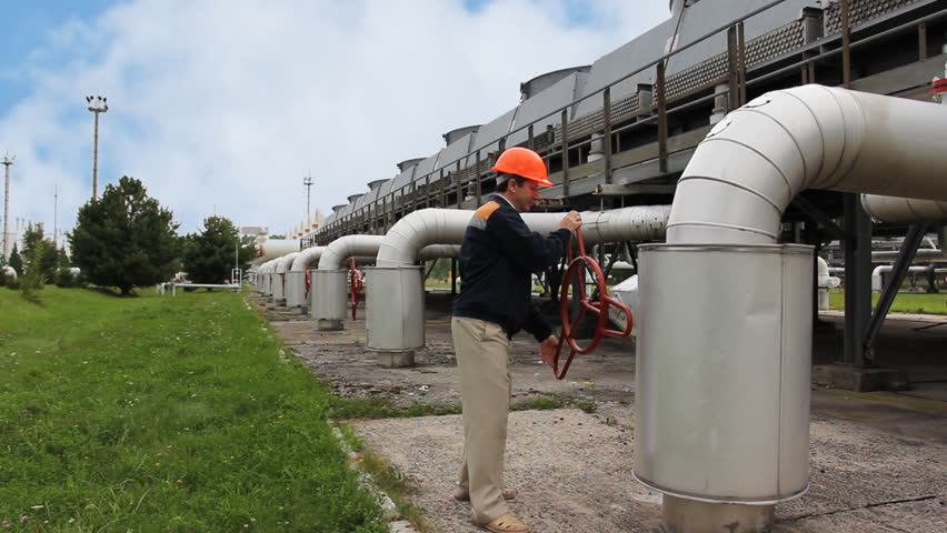 worker twists opening valve on unit of cooling gas compressor station