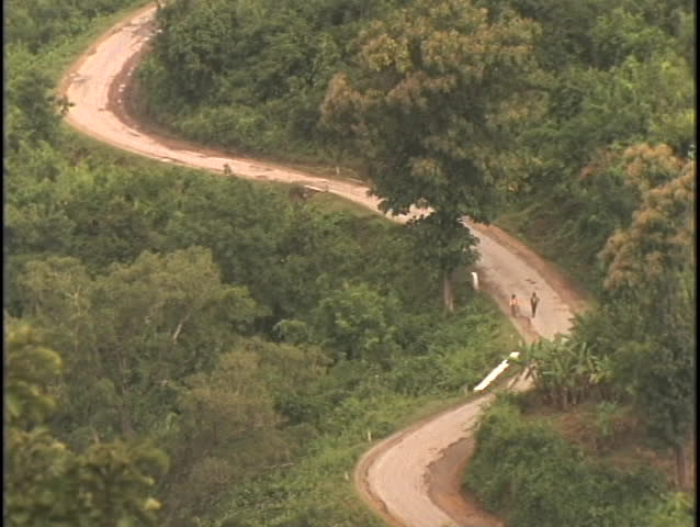 Native Burmese walk a dirt road through the jungle.