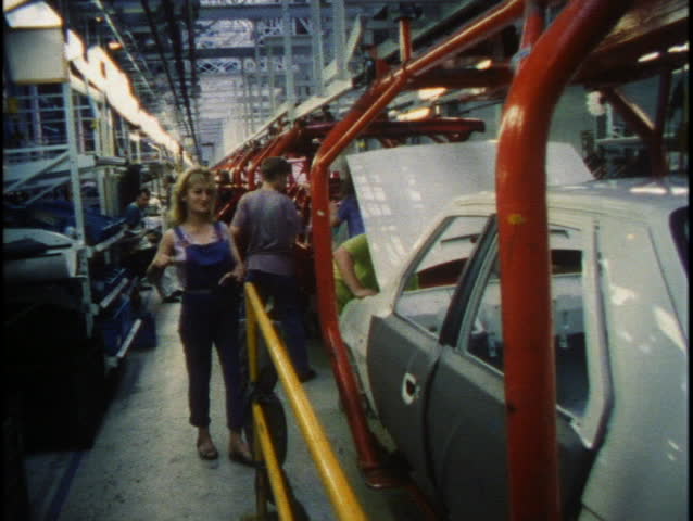 CZECH REPUBLIC - CIRCA 1990's: Men and women work together on an auto assembly line circa 1990's in the Czech Republic.