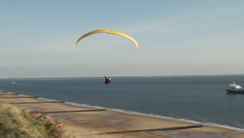 Parasailer sailing over the dunes and the beach along the coast of the province Zeeland in the Netherlands. 