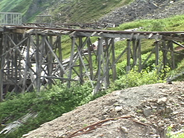 A collapsed wooden bridge surrounds part of a mountain.