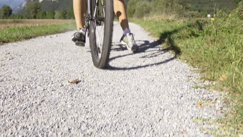 sport: young adult cyclist riding mountain bike in the countryside and smiling at camera. Crane shot