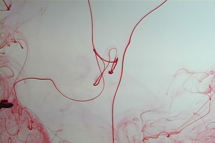 Red ink elegantly flowing in a liquified chamber.