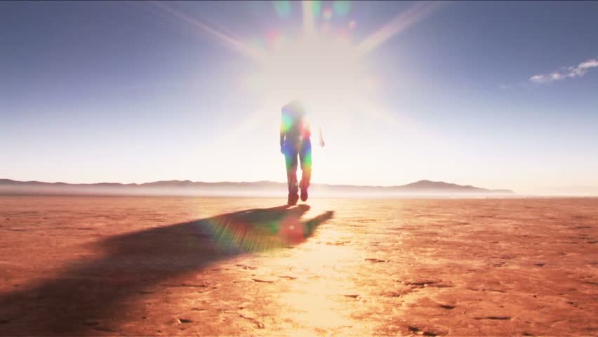 Man walking toward and past camera (desert - low shot)