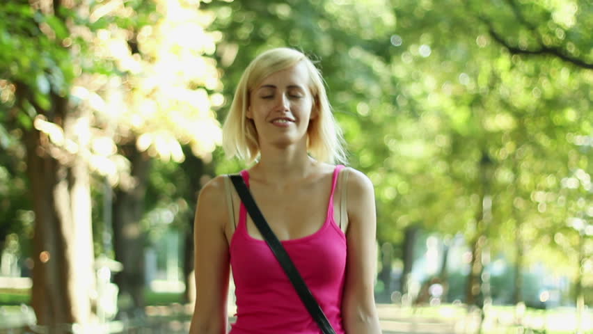 Happy young woman with shopping bags walking in the park, camera stabilizer shot