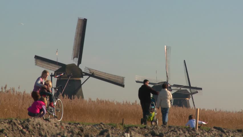 Dutch citizens walk on a footpath in front of windmills, 