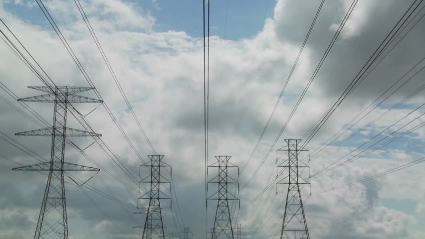 Time lapse of clouds moving behind high tension wires and power lines.