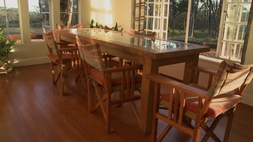 Giraffes stick their heads into the windows of an old mansion in Africa and eat off the dining room table.